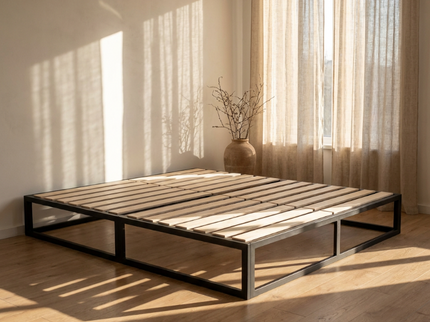 Zijaanzicht van het zwarte metalen bedframe Torino met houten lattenbodem naast gordijnen